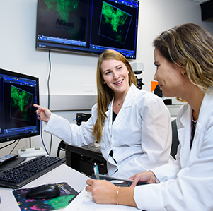 Two female students in a lab looking at a computer